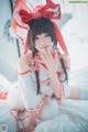 A woman in a red and white outfit sitting on a bed.