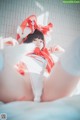 A woman in a red and white outfit laying on a bed.