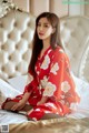 A woman in a red kimono sitting on a bed.