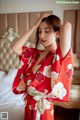 A woman in a red kimono standing on a bed.