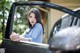 A woman leaning out the window of a black car.