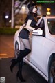 A woman leaning on the hood of a white car.