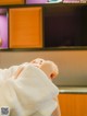 A woman in a white robe sitting in front of a television.