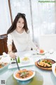 A woman sitting at a table with plates of food.