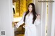 A woman in a white robe standing in front of a door.