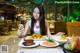 A woman sitting at a table with plates of food.