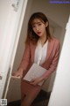 A woman in a pink suit holding a piece of paper.