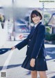 A woman in a school uniform is walking down the street.