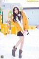 A woman in a yellow jacket is standing in the snow.