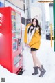 A woman standing in front of a coca cola vending machine.