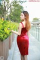 A woman in a red dress standing next to a planter.