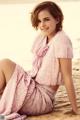 A woman in a pink dress sitting on the beach.