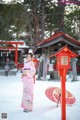 A woman in a pink kimono standing in the snow.