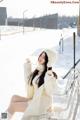 A woman sitting on a bench in the snow.