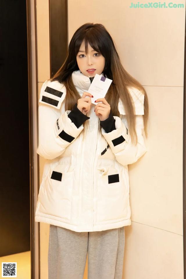 A woman standing in front of a wall holding a card.