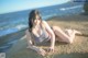 A woman in a bikini laying on a rock by the ocean.