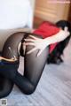 A woman in black stockings and high heels laying on the floor.