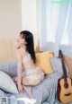 a woman sitting on top of a bed next to a guitar