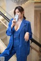 A woman in a blue suit holding a cell phone.