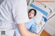 A woman laying in a hospital bed next to a nurse.