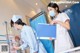 A woman in a white lab coat and a nurse in a blue uniform.