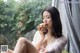 A woman sitting on a window sill eating an apple.