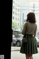 A woman standing in front of a window looking out at a city street.