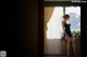 A woman in a blue dress sitting on a window sill.