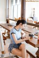 A woman sitting at a table looking at her cell phone.