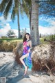 A woman in a colorful dress standing next to a palm tree.