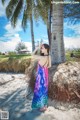 A woman in a colorful dress standing next to a palm tree.