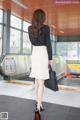 A woman in a black shirt and white skirt is walking down an escalator.