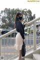 A woman wearing a black face mask standing on a railing.