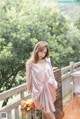 A woman in a pink dress standing on a balcony.