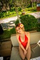 A woman in a red bathing suit sitting on a lounge chair.