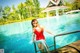 A woman in a red bathing suit standing on the edge of a swimming pool.