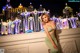 A woman in a green dress posing in front of a fountain.