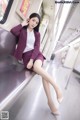 A woman in a purple suit sitting on a subway train.