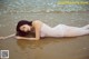 A woman laying on the beach in a white bodysuit.