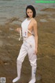 A woman in a white outfit standing on a beach.