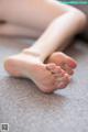 A close up of a person's bare feet on a couch.