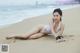 A woman in a white bikini laying on the beach.