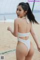 A woman in a white bikini standing on a beach.