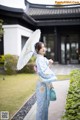 A woman in a blue kimono holding an umbrella.