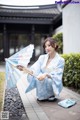 A woman in a blue kimono holding an umbrella.