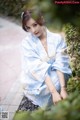 A woman in a blue and white kimono sitting on the ground.