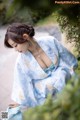 A woman in a blue and white kimono sitting on the ground.