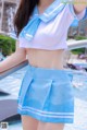 A woman in a blue and white uniform posing by a pool.