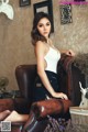 A woman sitting on a brown leather chair in a room.