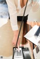 A woman in a white shirt is talking on a telephone.